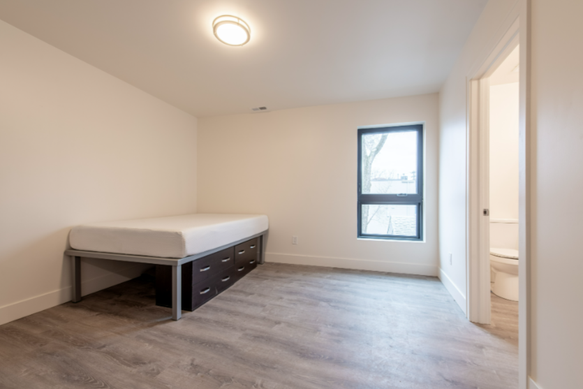 A bedroom with a bed, a window, and a door.